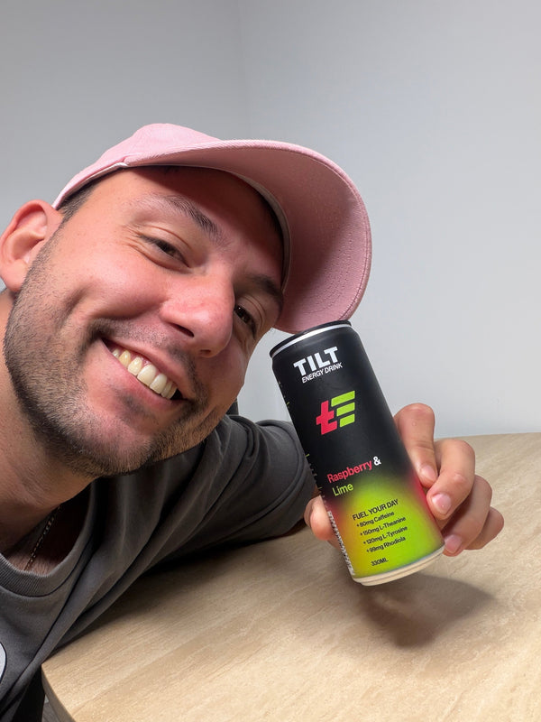 Man holding a TILT Raspberry Lime energy drink can with a grey background